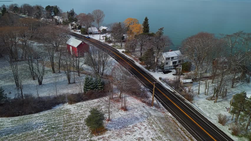 Aerial view, snowy road, lakefront homes, winter landscape.