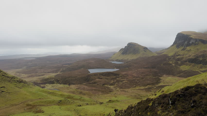Panoramic ground shot of The Quiraing, Isle of Skye. Dramatic landslip formations, mountain lakes and peaks under heavy cloud. Moody Scottish footage