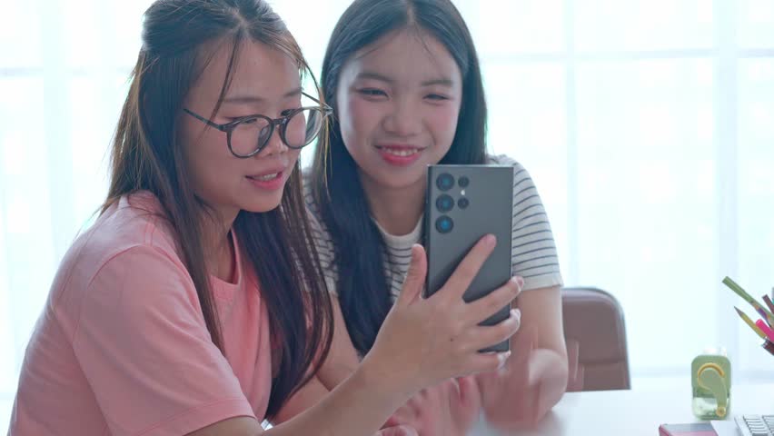 Two Asian girls using smartphone take selfie.