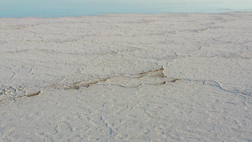 Aerial view of the vast white salt crusts and cracked earth of the Danakil Desert under a clear sky in Dalol, Afar, Ethiopia.