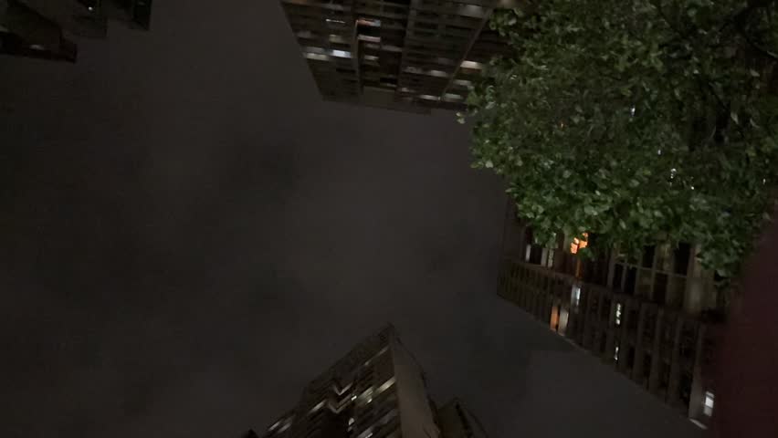 Urban thunderstorm with dark fast clouds and a bright lightning bolt hitting downtown skyscrapers.