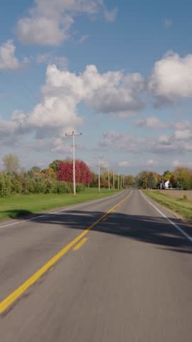 Slow motion driving on empty road through peaceful farmland.