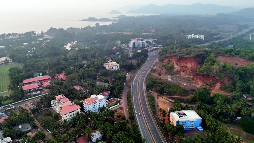 Drone shot capturing the tropical landscape near Palolem Beach, with lush coconut groves, resort buildings, and a long highway stretching through layered greenery. Goa-Karnataka costal highway