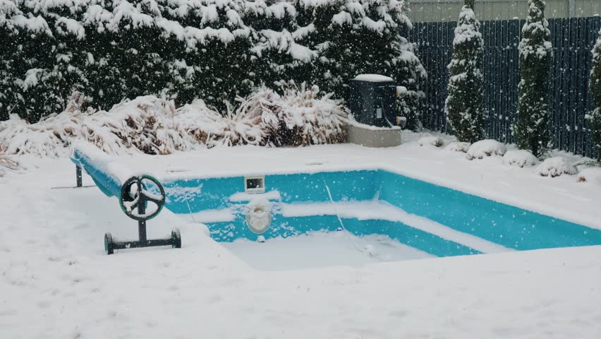 Snowy winter scene backyard pool, frozen, winter landscape, snow falling.