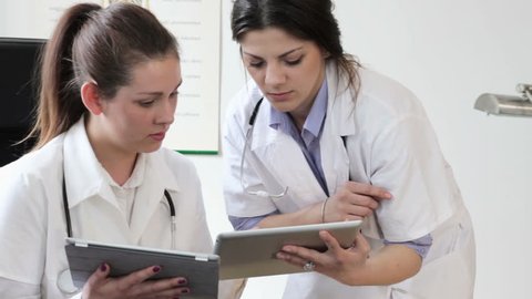 Two female doctors with tablet computers, tracking shot