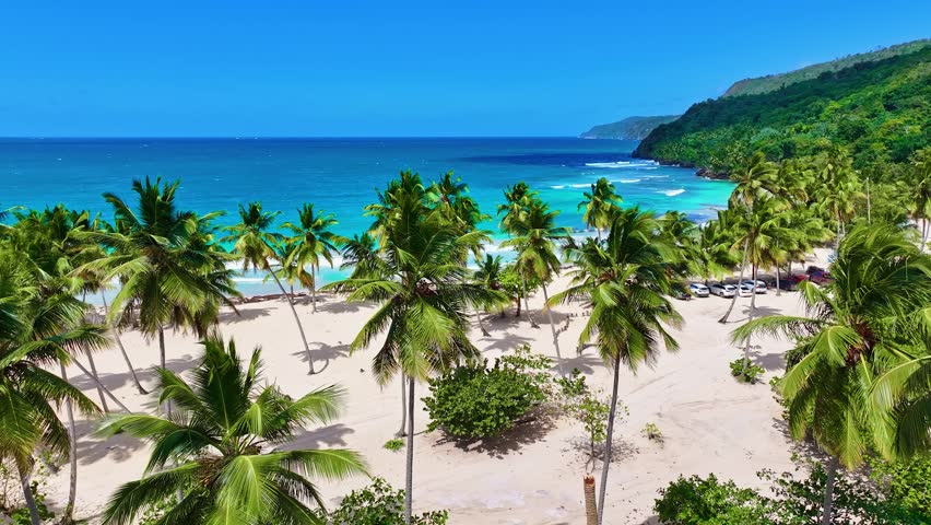 A tropical beach with white sand, turquoise sea, and palm trees in the morning sunlight. Drone view of the picturesque nature of Asia. Blue sea, lagoons, and palm trees. A luxurious place to relax.