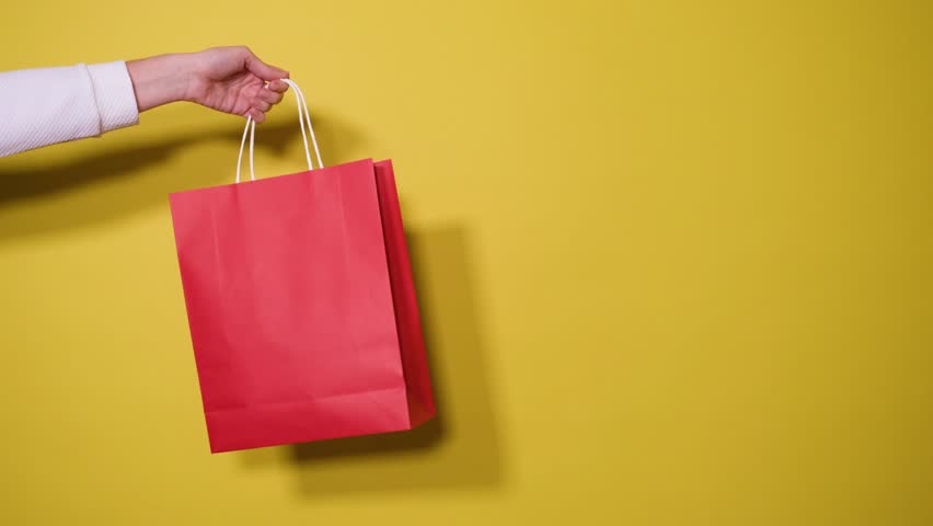 Hands holding red shopping bags with 40 off discounts on yellow background