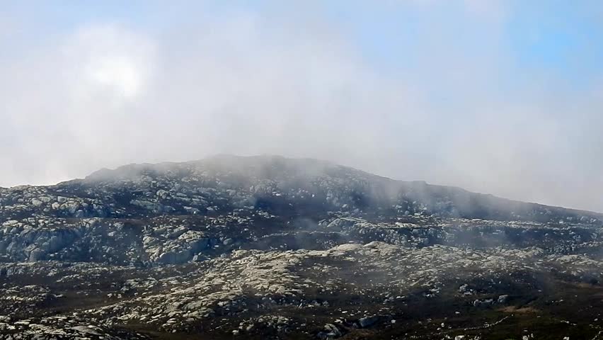 Looking up as white clouds pass across rocky limestone mountain summit wild nature