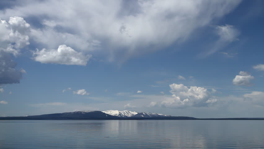 Snowcapped mountains reflecting on calm lake in Yellowstone. The tranquil freshwater landscape highlights the vast scale and untouched wilderness of the national park. A peaceful panoramic scene showcasing the dramatic natural beauty of Wyoming’s iconic mountain terrain.