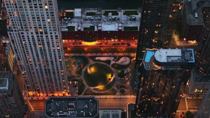 Top down view of an illuminated urban park nestled between tall skyscrapers in Chicago.