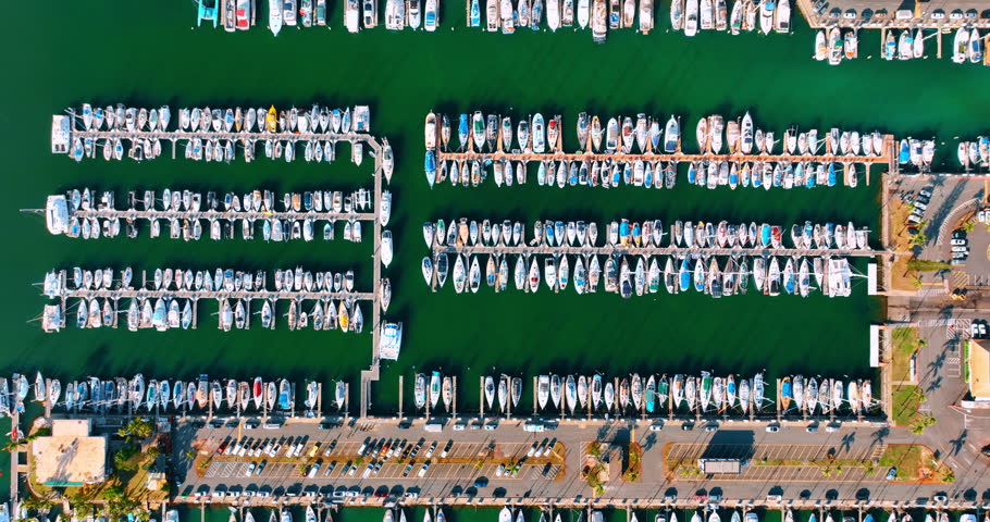 Rows of modern boats at the berths of the yacht club. Top view on the water vehicles near the shore of Honolulu, Hawaii, USA.