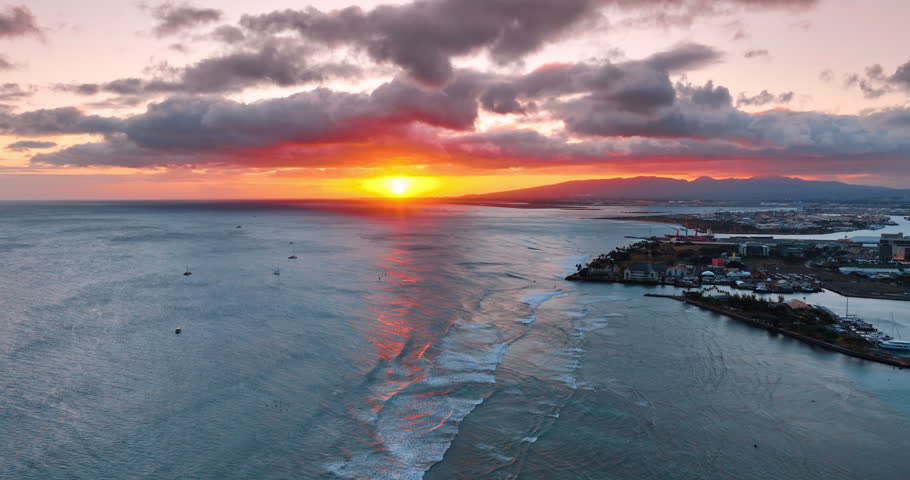 Amazing sunset over the Pacific Ocean at the shore of the Hawaii. Some boats on the anchor of the waterscape. Aerial view.