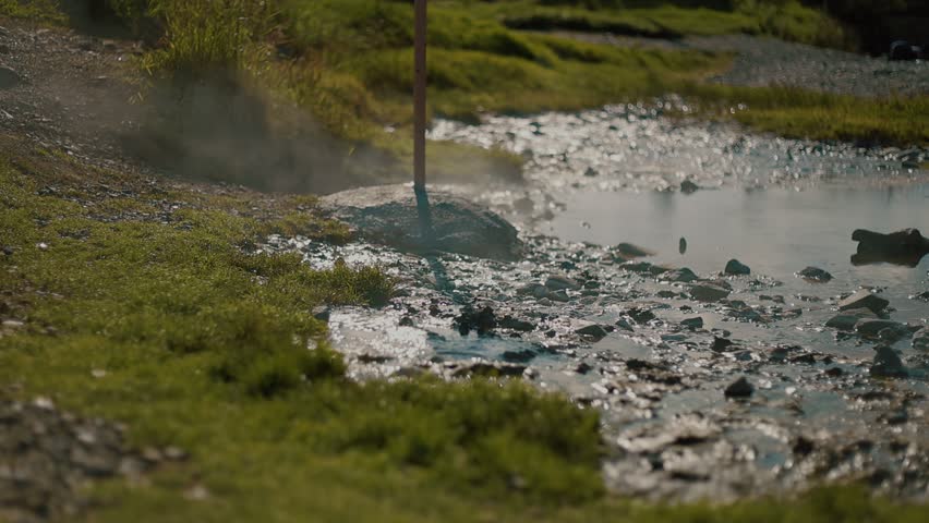 Large puddle of steaming hot spring water reflecting silhouettes of people on its surface. Tourists come to thermal springs for health improvement.
