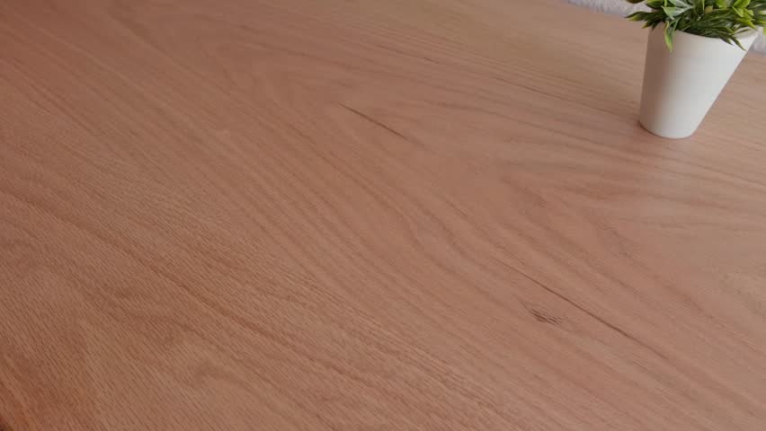 Unrecognizable person rolling out an orange desk mat on a wooden table.
