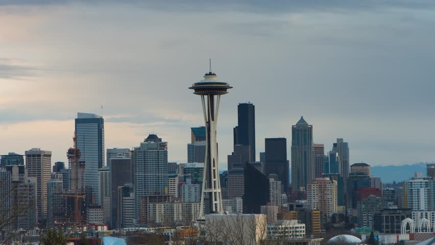 This 4K video shows the Seattle skyline featuring the Space Needle. The visual documents the observation tower structure, the dense arrangement of metropolitan skyscrapers, and the regional geography of the Pacific Northwest. The composition illustrates urban engineering and Puget Sound topography, documenting Washington State