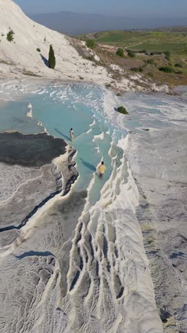 A couple experiences the breathtaking beauty of Pammukale, Turkey, where natural terraces create dazzling pools of turquoise water.
