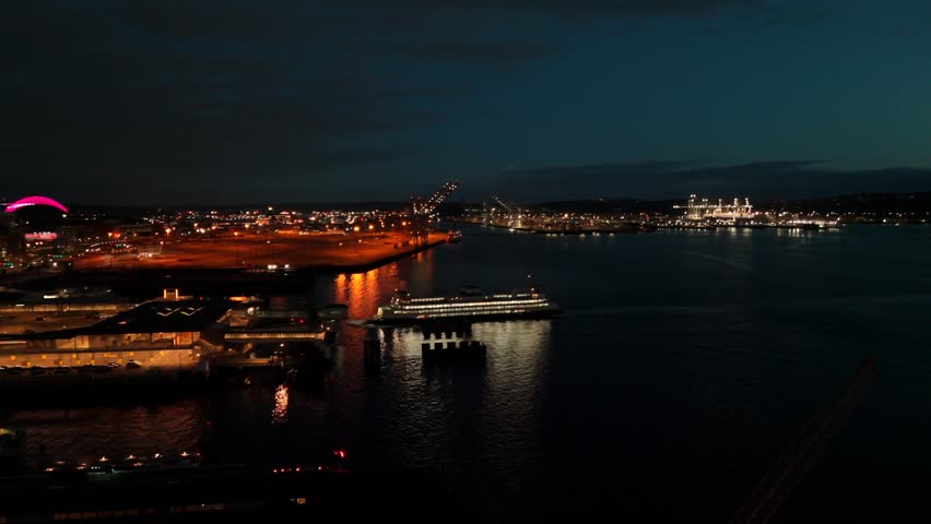 Aerial drone view of Seattle harbor at night with ferry crossing Elliott Bay