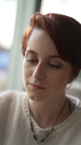 Portrait of a young red hair woman smiling at camera in vertical video. Happy 20 girl face