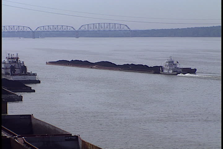 METROPOLIS, ILLINOIS - MAY 20, 1999: Long coal barge on Ohio River, camera zooms in to cargo bins full of coal in Cook Coal Terminal.