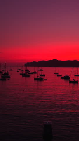 Stunning red sunset over a calm sea with anchored sailboats in mallorca