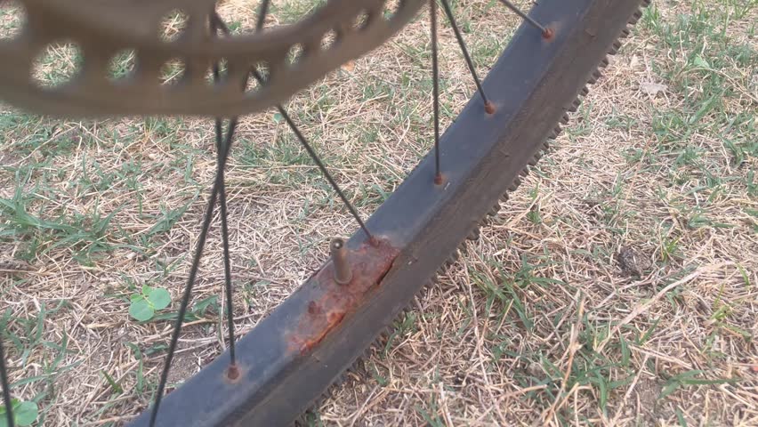 Rusty Bicycle Wheel Rim and Spokes on Dry Grass Ground