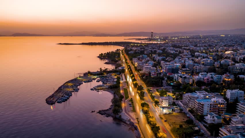 Aerial hyperlapse view of the southern coast of Athens, Greece, with Voula district, boat marinas and street traffic during evening time