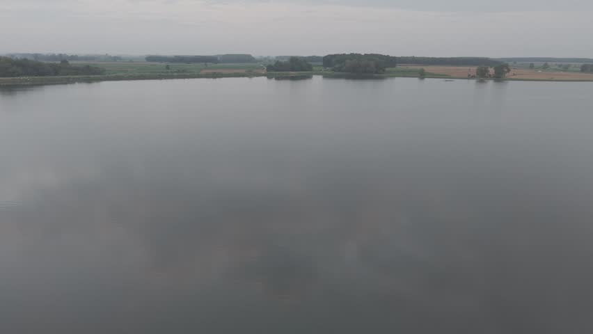 Calm lake water reflecting the surrounding landscape on an overcast day