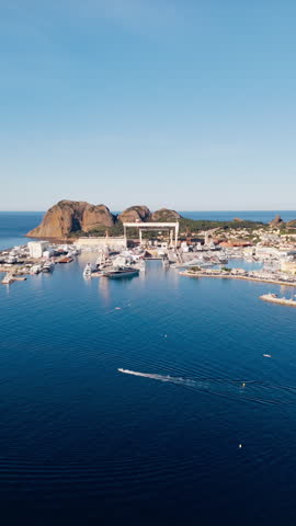 Small boat underway along coastline near shipyard in La Ciotat, southern France. Mediterranean harbor with yachts and industrial buildings