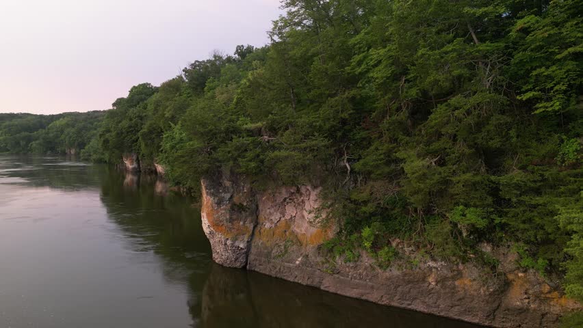 Panning across the Cedar River, near Cedar Rapids at sunrise to see the cliffs and the water below. 4k, drone, flying