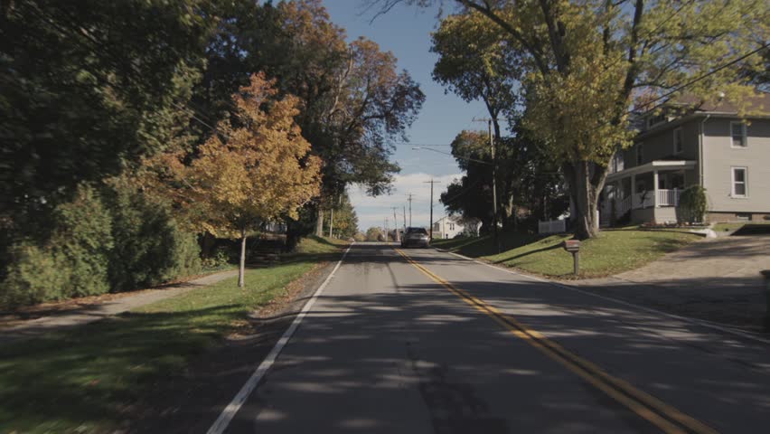 Motion camera driving through residential area with fall foliage.