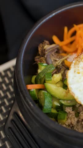 Close-up shot of red chili paste poured over rice, vegetables, and a fried egg