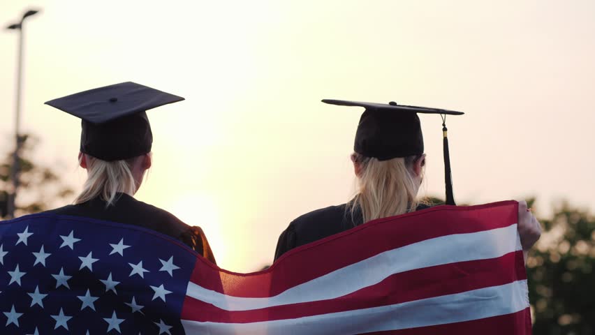 Graduation celebration, two students, American flag, sunset victory.