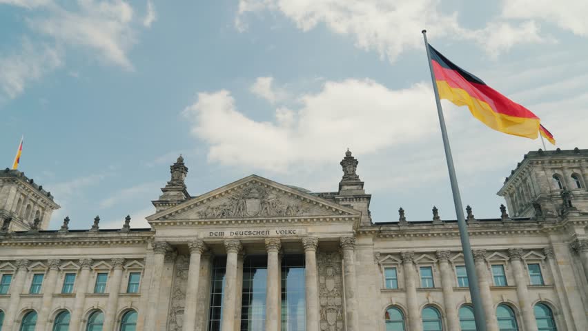Historic landmark architecture, fluttering flag, sunny day in Berlin.