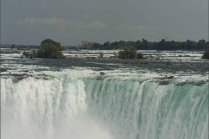 Water flows from the Niagara River and cascades over the edge of Horseshoe Falls at Niagara Falls, Ontario, Canada.