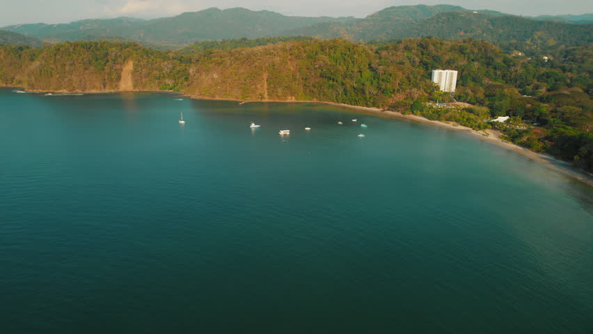 Boats floating in a calm bay surrounded by lush green hills in Punta Leona shore Costa Rica