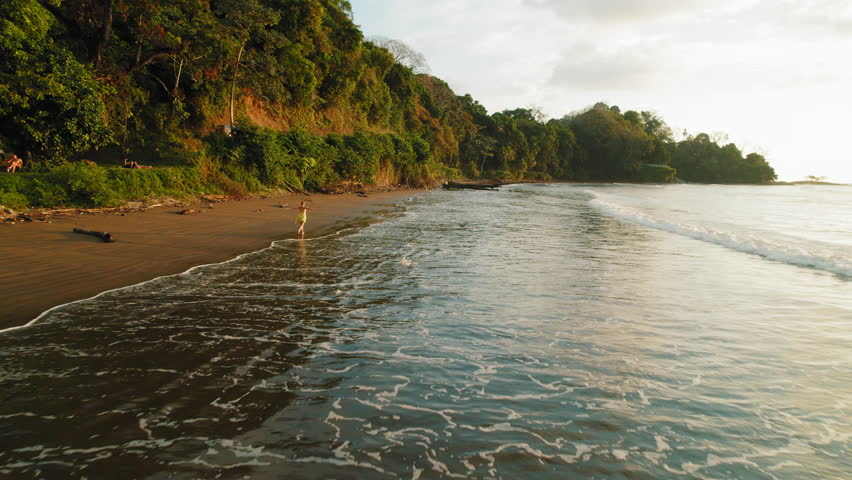 Person with open arms enjoying sunset at tropical sandy beach in Costa Rica