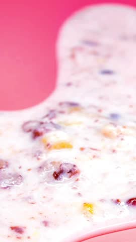 High angle close up of a scoop of delicious berry ice cream melting slowly on a vibrant bright pink background