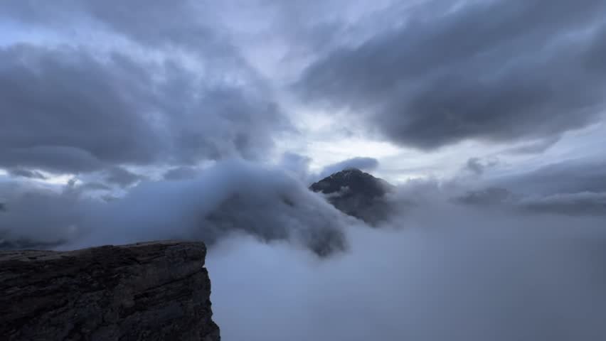 Spectacular twilight timelapse capturing thick clouds rolling over a majestic peak in the Himalayan Grand Canyon of Tibet China.