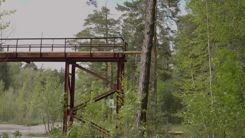  Industrial metal structure with yellow pipe in a pine forest