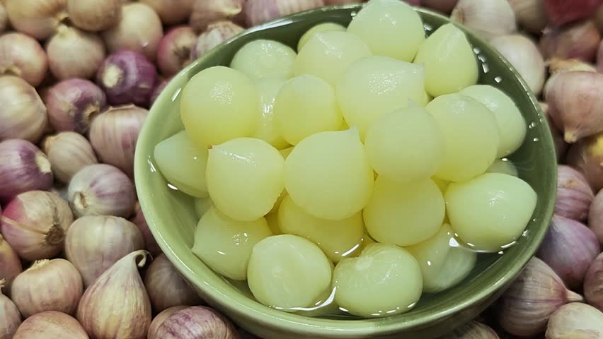 Pickled garlic in a green cup.