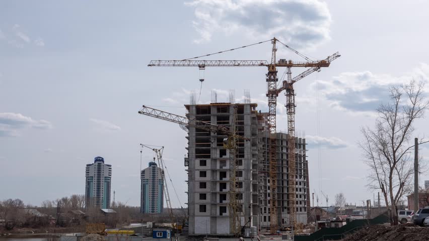 Timelapse of high rise building construction with several tower cranes working simultaneously on a large urban development site Modern city architecture and engineering process