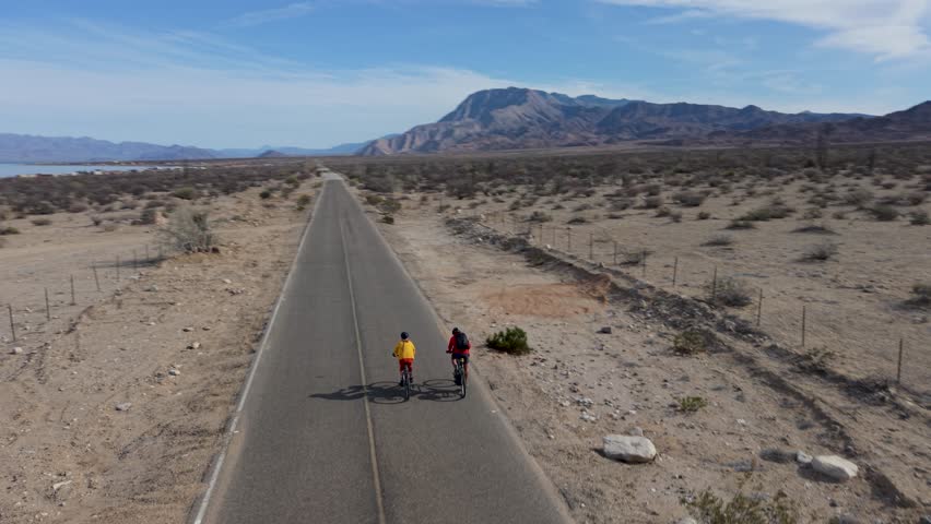 A mature couple bikes along a road near La Gringa by Bahia De Los Angeles on the Sea of Cortez in Baja California, Mexico.