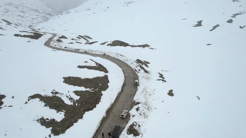 Aerial drone shot following the winding Shingo La pass road surrounded by snow covered fields among the Himalaya mountains showing the transport infrastructure in Ladakh Leh Sissu India