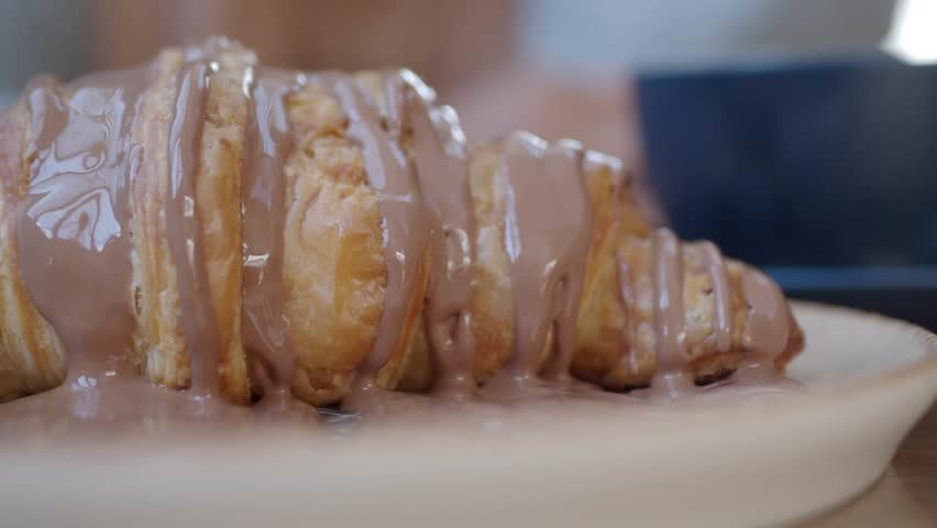 Enjoying a croissant drizzled with rich chocolate sauce