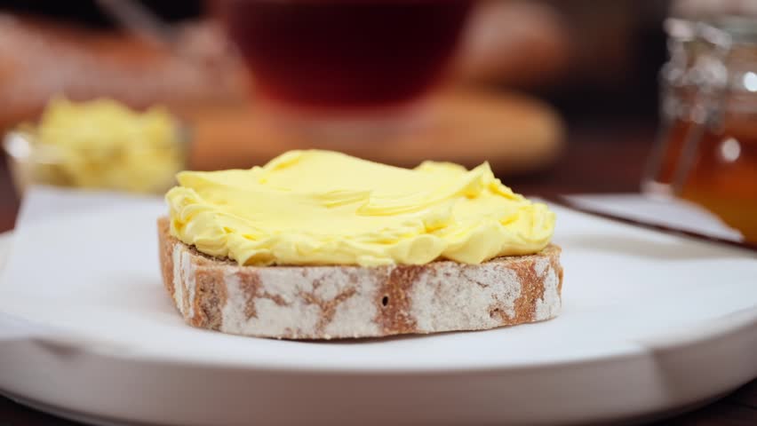 Butter spreading on fresh bread slice, close up homemade breakfast scene, copy space
