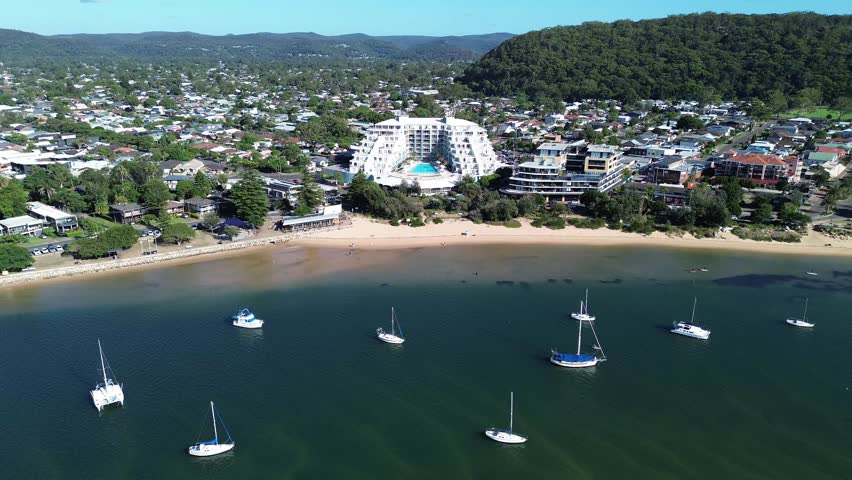 drone view Ettalong beach NSW Australia.View of the bay with boats and a town by the water on a sunny day near a large hill in New South Wales