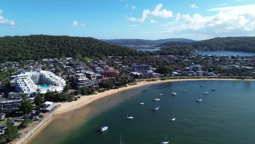 drone view Ettalong beach NSW Australia.View of the bay with boats and a town by the water on a sunny day near a large hill in New South Wales