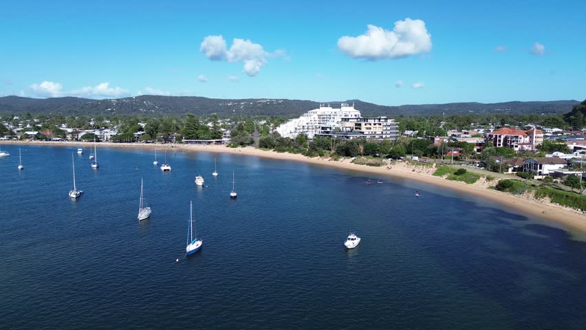 drone view Ettalong beach NSW Australia.View of the bay with boats and a town by the water on a sunny day near a large hill in New South Wales