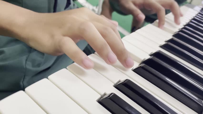 Close up shot of hands playing a modern electronic keyboard synthesizer.