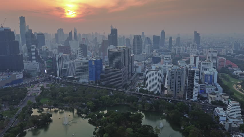 Aerial view of Bangkok city skyline during sunset. Urban skyscrapers and Lumpini park in business district, Thailand, 4k